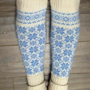 May include: A pair of white knitted leg warmers with a blue snowflake pattern.