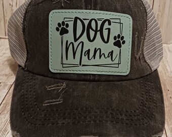 May include: Black distressed trucker hat with a light blue patch that says "DOG Mama" with paw prints on either side.