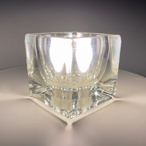 May include: A clear glass cube-shaped vase with a reflective surface.