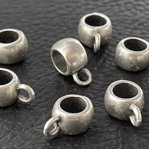 May include: Eight silver-toned metal bead caps with a loop on the side. The bead caps are round and have a smooth finish.
