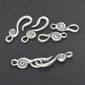 May include: A collection of silver-toned metal jewelry clasps featuring a spiral design. The set includes two S-shaped hook components and two matching loop components, with one pair shown connected together to demonstrate the functional closure mechanism.