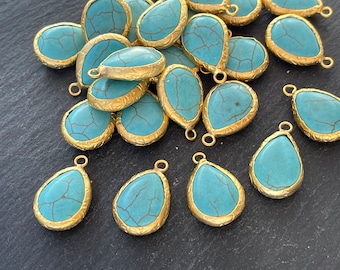 May include: A group of turquoise blue teardrop-shaped pendants with gold-toned metal settings. The pendants have a marbled pattern and are perfect for jewelry making.