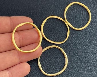 May include: Four gold-colored metal rings of varying sizes. The rings are smooth and have a slightly irregular shape.