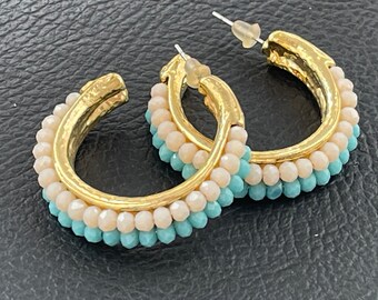 May include: Gold hoop earrings with a double row of light blue and cream colored beads.