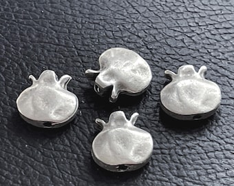 May include: Four silver-toned metal beads shaped like pomegranate fruits. Each bead features a smooth, rounded body with a small, raised crown-like protrusion at the top and a visible hole at the base for threading, showcasing a metallic finish.
