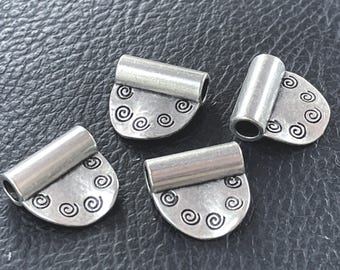 Könnte beinhalten: Vier silberfarbene Metall-Schmuckschlaufen, jede mit einer halbkreisförmigen flachen Basis, die mit kleinen, eingravierten schwarzen Spiralmustern verziert ist, und einem zylindrischen Röhrchen oben zum Durchziehen einer Kette.