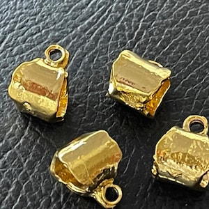May include: Four gold-toned metal end caps for jewellery making. Each cap has a unique, slightly irregular shape.
