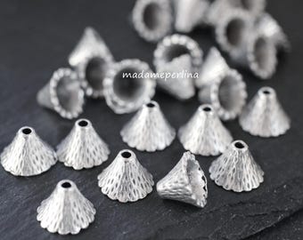 Op de afbeelding: Een verzameling zilverkleurige metalen kraalkappen met een getextureerd, gehamerd oppervlak en een conische vorm. Elk stuk heeft een klein gaatje aan de bovenkant en een geschulpte rand aan de basis. De tekst madameperlina is in het midden zichtbaar.