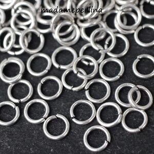 May include: A close-up of a pile of silver jump rings. The rings are small and round, and they are perfect for jewelry making.