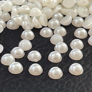 Könnte beinhalten: Ein Set aus drei Keramikbechern mit gesprenkelter, matter Oberfläche. Die Becher sind in Creme-, Hellgrau- und Dunkelgrautönen gehalten. Jeder Becher hat ein schlichtes, minimalistisches Design.