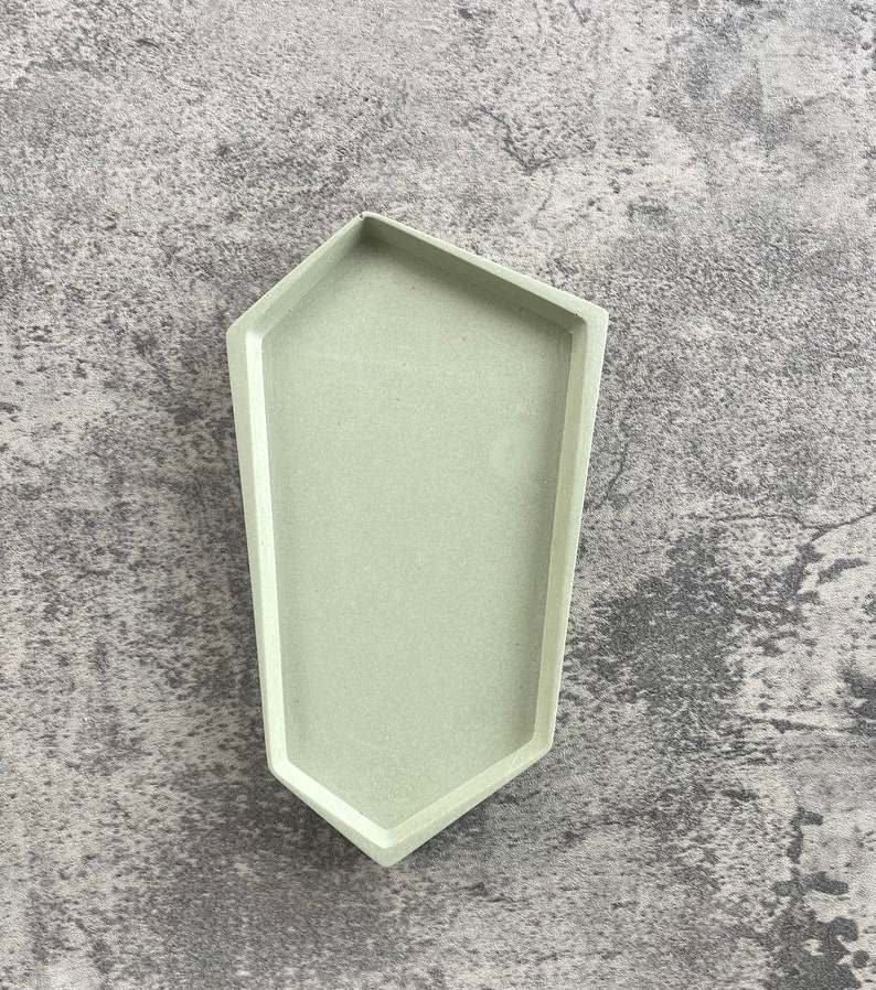 May include: A light green geometric tray with a hexagonal shape. The tray is made of concrete and has a smooth, matte finish.
