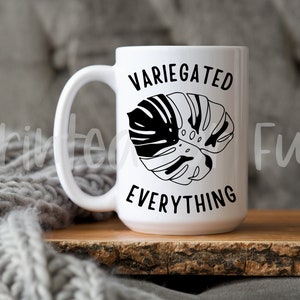 May include: White ceramic mug with a black and white illustration of a monstera leaf and the text "VARIEGATED EVERYTHING".
