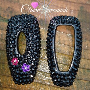 May include: Two black key covers with a diamond-like finish. One key cover has pink and purple rhinestones. The key covers are labeled "Claire Savannah Designs".