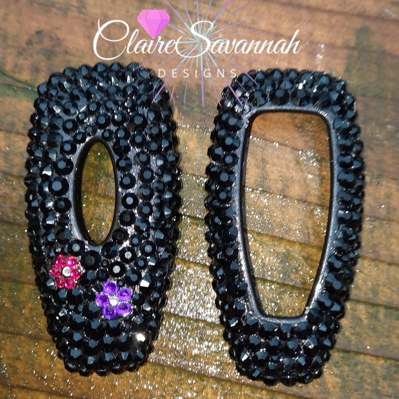 May include: Two black key covers with a diamond-like finish. One key cover has pink and purple rhinestones. The key covers are labeled "Claire Savannah Designs".