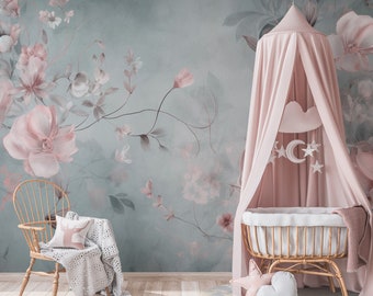 May include: A nursery scene with a floral wallpaper backdrop in shades of blue and pink. A wooden crib with a pink canopy and decorative mobile hangs above. A wooden chair with a pillow and blanket sits to the left. A rug with heart and star pillows is on the floor.