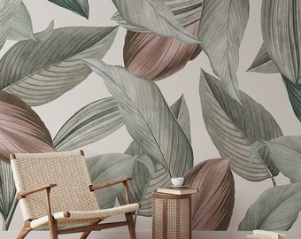 May include: A room featuring a large-scale botanical wallpaper with oversized leaves in shades of green and mauve. A woven chair with wooden arms and legs sits in front of the wall. A small side table and books complete the scene, creating a relaxing, nature-inspired interior.