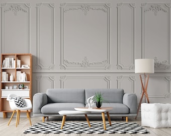 May include: A modern living room with gray walls featuring decorative molding. The room includes a gray sofa, a white and wood coffee table, a wooden bookshelf, a white chair, and a black and white patterned rug.
