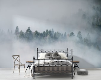 May include: A bedroom scene featuring a wrought iron bed with a gray comforter and pillows. A forest scene with fog is on the wall behind the bed. A wooden chair and side tables are also in the room. The overall theme is nature and tranquility.