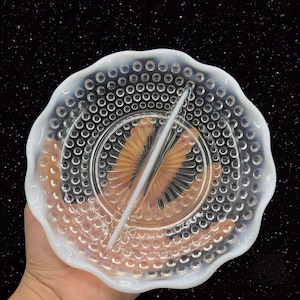 May include: A white milk glass divided serving dish with a scalloped edge and a raised dot pattern. The dish has two sections separated by a divider.