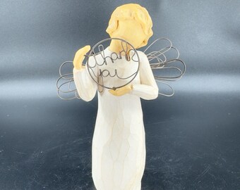 May include: A white wooden angel figurine holding a wire heart with the words "Thank You" inscribed on it. The angel has a yellow head and wings made of wire.