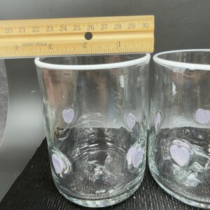 May include: Two clear glass tumblers with a heart design. A wooden ruler with centimetre markings is placed above the glasses. The ruler shows measurements from 50.8 to 76.2 cm.
