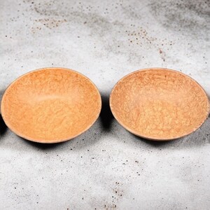 May include: Three empty, light brown, wooden bowls with a marbled pattern on a gray background.