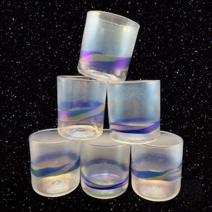 May include: Six iridescent glass tumblers with a blue and gold stripe design. The glasses are stacked in a pyramid shape.