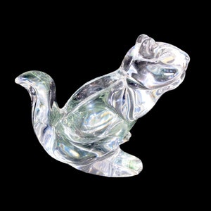 May include: A clear glass sculpture of a squirrel in a sitting position. The sculpture is detailed and has a realistic appearance.