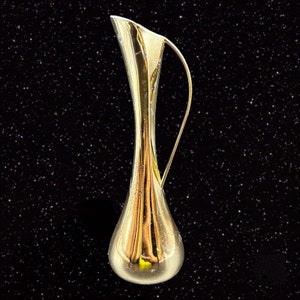 May include: A tall, gold-colored pitcher with a slender neck and a curved handle. The pitcher has a bulbous base and a flared opening. The background is a dark, starry night.