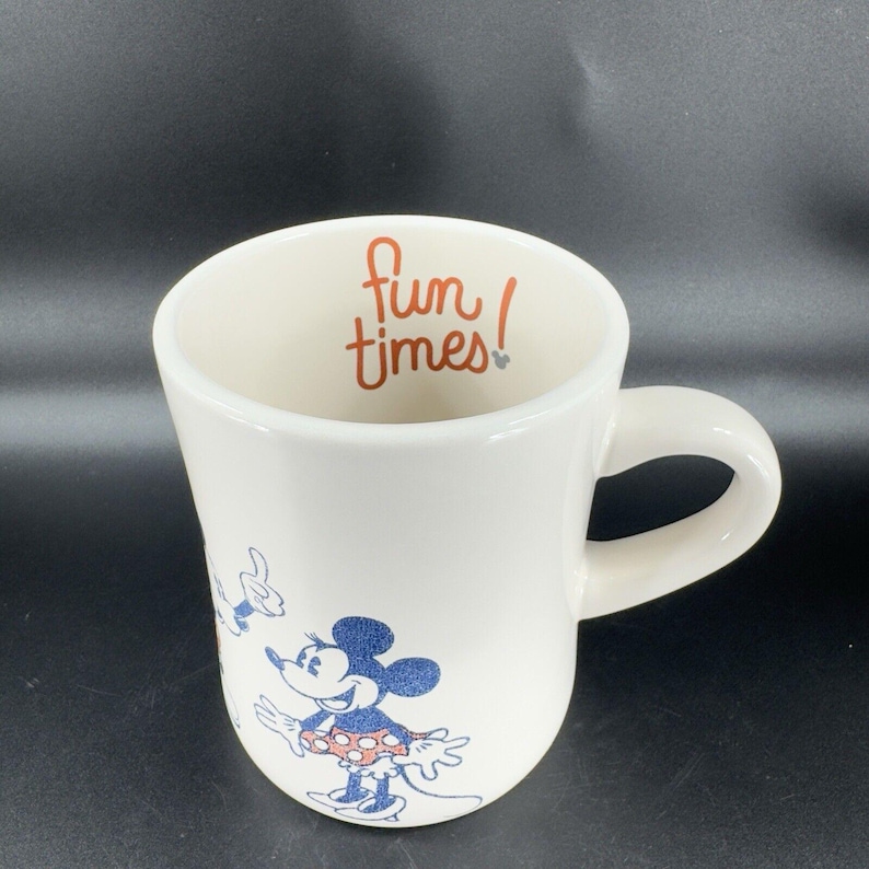 May include: White ceramic mug with a blue and red illustration of Mickey Mouse and Minnie Mouse. The inside of the mug has the text "fun times!" in orange.