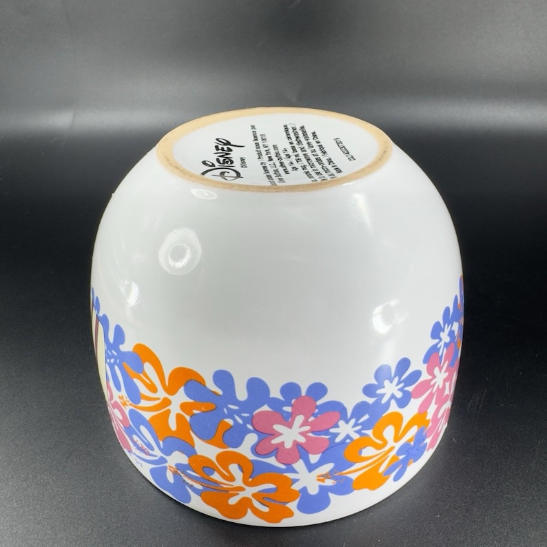 May include: White ceramic bowl with a floral design in orange, blue, and pink. The bowl has the word "Disney" printed on the bottom.