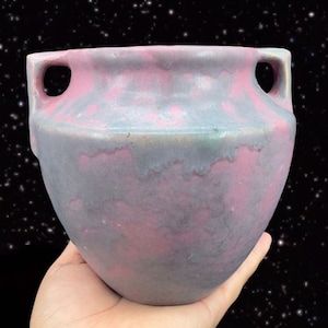 May include: A vintage ceramic vase with two handles. The vase is a light blue and pink color with a marbled glaze.