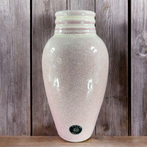 May include: A pink ceramic vase with a textured surface and a white rim. The vase has a round body and a narrow neck. It is made in the USA.