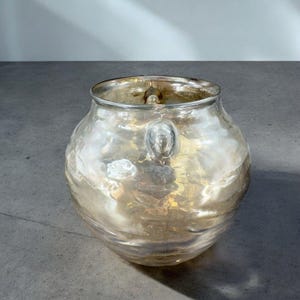 May include: A clear glass vase with a textured, iridescent finish. The vase has a round body and two small handles.