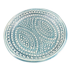May include: A blue ceramic plate with a white paisley design. The plate has a raised rim and a smooth finish.