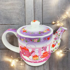May include: A purple and pink teapot with a floral design. The teapot has a lid and a handle. The teapot is decorated with a scene of a teapot, a cup, a plate with a pastry, and a butterfly.