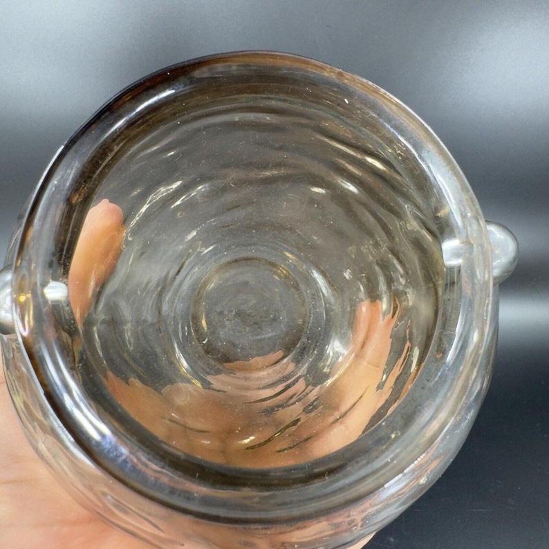 May include: A clear glass jar with a textured surface and a wide opening. The jar has a silver rim and two silver handles.