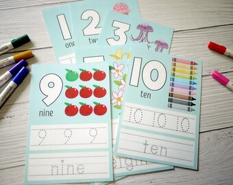 May include: Educational flashcards with numbers 1-10, featuring illustrations of objects and tracing exercises. The cards are light blue with colorful graphics, including apples, jellyfish, and crayons. Markers are visible on the sides.