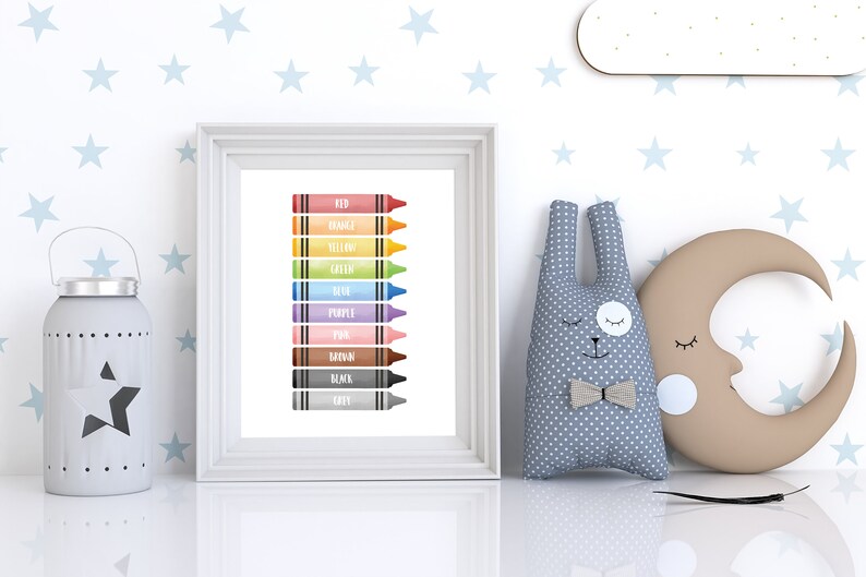 May include: A framed print featuring a colorful illustration of crayons, each labeled with a different color name. The crayons are arranged vertically, with colors including red, orange, yellow, green, blue, purple, pink, brown, black, and gray. The print is displayed on a white surface.