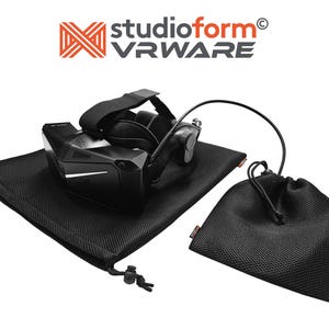 May include: A black VR headset with a black mesh carrying bag and a smaller black mesh drawstring bag. The headset has a black strap and a black cord. The text "studioform VRWARE" is visible in the top center of the image.