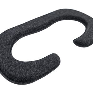 May include: A dark gray, curved VR headset facial interface replacement. The accessory is made of a soft, textured material and is designed to fit around the eyes and nose for comfort during virtual reality use.