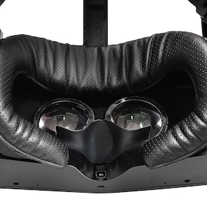 May include: Black VR headset with a padded leather headband and two clear lenses.
