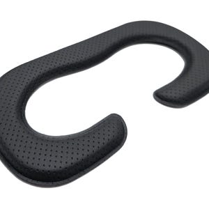 May include: Black, curved VR headset facial interface replacement. The pad is made of a soft, perforated material for comfort. The shape is designed to fit around the eyes and nose, with a curved design for the forehead and cheeks.