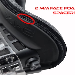 May include: Close-up of a black protective goggle with the text "2 MM FACE FOAM SPACERS" in red. The goggle has a clear, transparent frame and a black, padded face cushion.