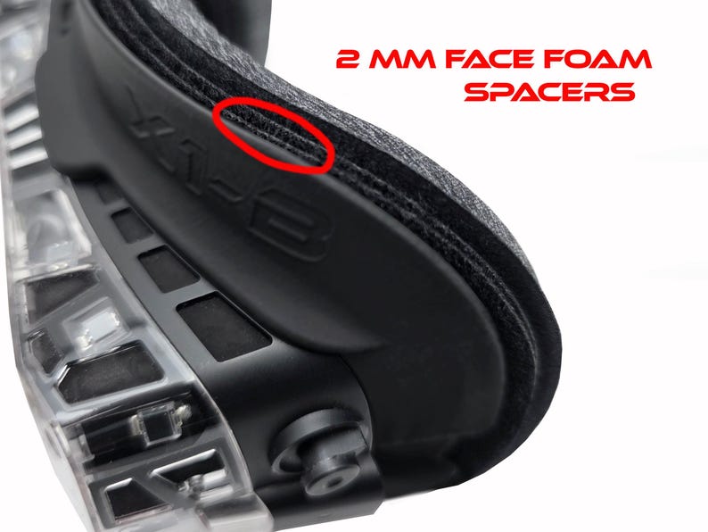 May include: Close-up of a black protective goggle with the text "2 MM FACE FOAM SPACERS" in red. The goggle has a clear, transparent frame and a black, padded face cushion.