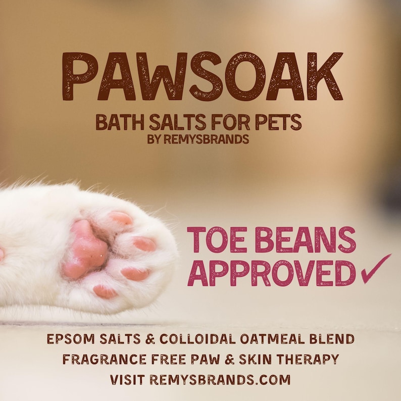 May include: A white cat paw with pink paw pads. The text "PAWSOAK BATH SALTS FOR PETS BY REMYSBRANDS" is at the top of the image. The text "TOE BEANS APPROVED✓" is in the lower right corner of the image. The text "EPSOM SALTS & COLLOIDAL OATMEAL BLEND FRAGRANCE FREE PAW & SKIN THERAPY VISIT REMYSBRANDS.COM" is at the bottom of the image.