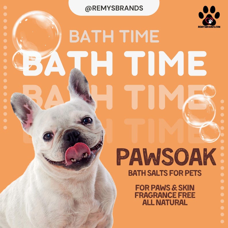 May include: A white French bulldog with its tongue sticking out, looking happy. The dog is in front of a peach-coloured background with the text "BATH TIME" repeated multiple times. The text "PAWSOAK BATH SALTS FOR PETS" is also on the background. Below that, the text "FOR PAWS & SKIN FRAGRANCE FREE ALL NATURAL" is displayed.