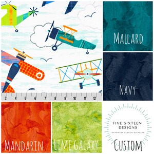 May include: A fabric design featuring colorful airplanes on a white background with blue brushstrokes. The image also shows swatches of textured fabric in teal, navy, orange, and lime green, with the words "MALLARD", "NAVY", "MANDARIN", and "LIME GALAXY".