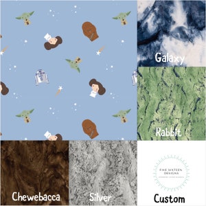 May include: A collection of custom blankets with various designs. One blanket features a light blue background with cartoon characters, including Yoda, Princess Leia, and Chewbacca. Other blankets have galaxy, rabbit, Chewbacca, and silver textures.