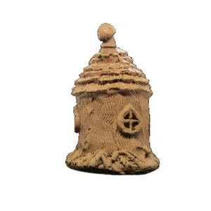 May include: A small, brown, ceramic fairy house with a pointed roof and a window. The house is decorated with a textured surface that resembles bark.